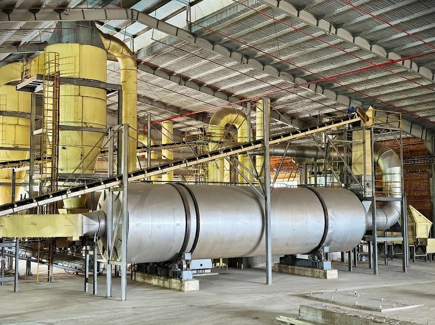 Rotary dryer drum with its feed conveyor and cyclone separators inside a working plant